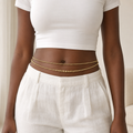woman in white wearing a gold double strand waist bead